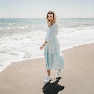 Frau am Strand im Kleid, glücklich