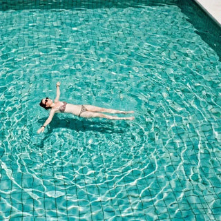 Eine Frau liegt entspannt auf dem Wasser im Pool