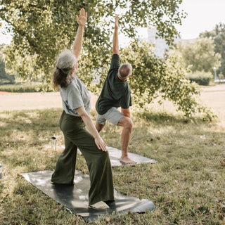 2 Menschen machen draußen Yoga zum entspannen und wohl fühlen