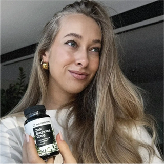 Eine Frau hält eine Flasche Vitamin C hoch, das aus natürlichen Elementen gewonnen wird.